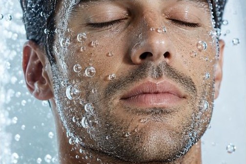 Visage d'homme aux yeux fermés sous une pluie de fines bulles d'eau